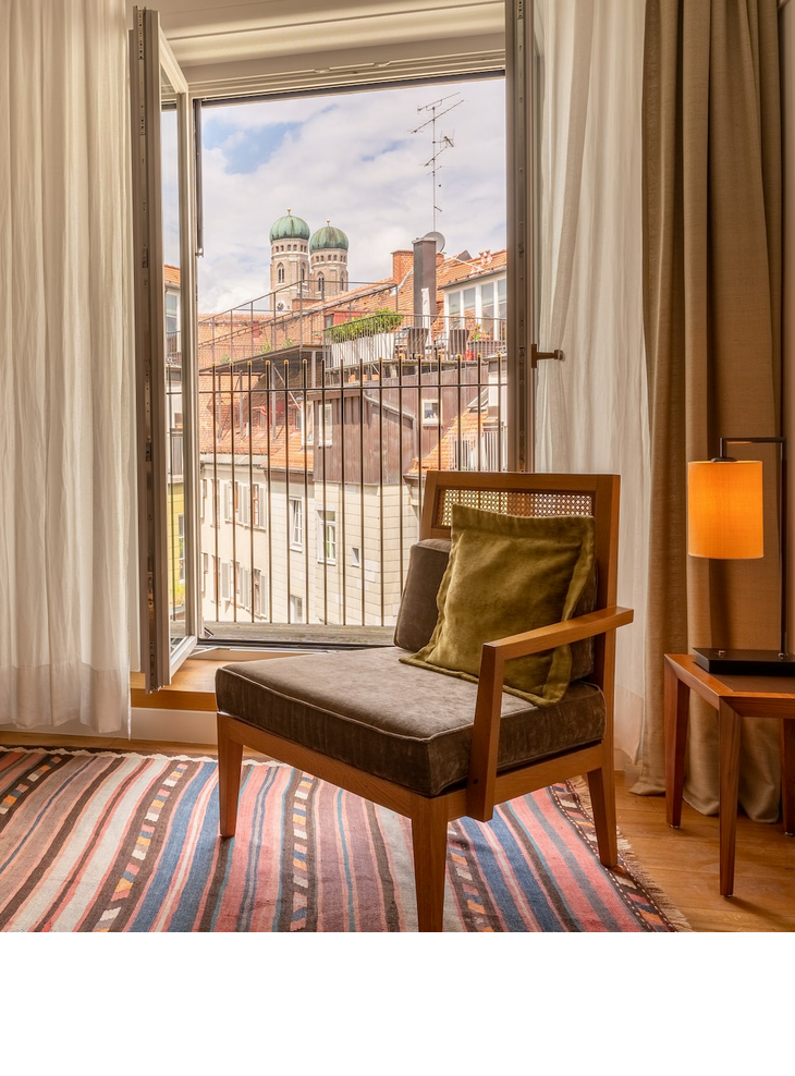 Wohnbereich mit Sessel im Hotelzimmer Market View, Fenster mit Blick auf Viktualienmarkt in München