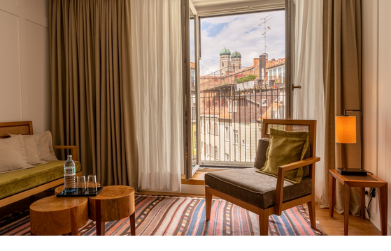 Wohnbereich mit Sessel im Hotelzimmer Market View, Fenster mit Blick auf Viktualienmarkt in München