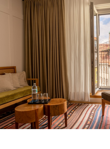 Wohnbereich mit Sessel im Hotelzimmer Market View, Fenster mit Blick auf Viktualienmarkt in München