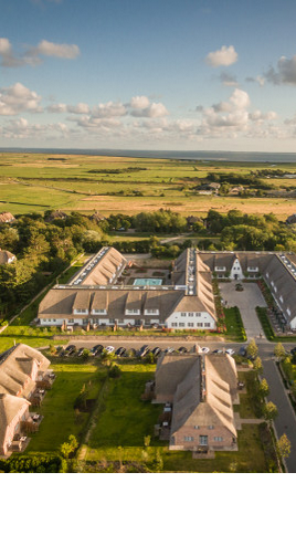 Luftaufnahme Hotel Severin*s auf Sylt Luftaufnahme des Severin*s Resort & Spa auf Sylt, umgeben von grüner Landschaft und malerischem Himmel.