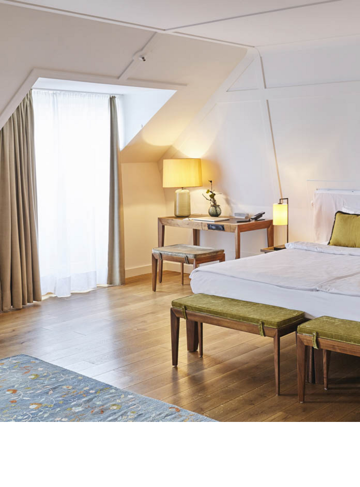 Großes Doppelbett und Schreibtisch in der Suite im LOUIS Hotel Muenchen