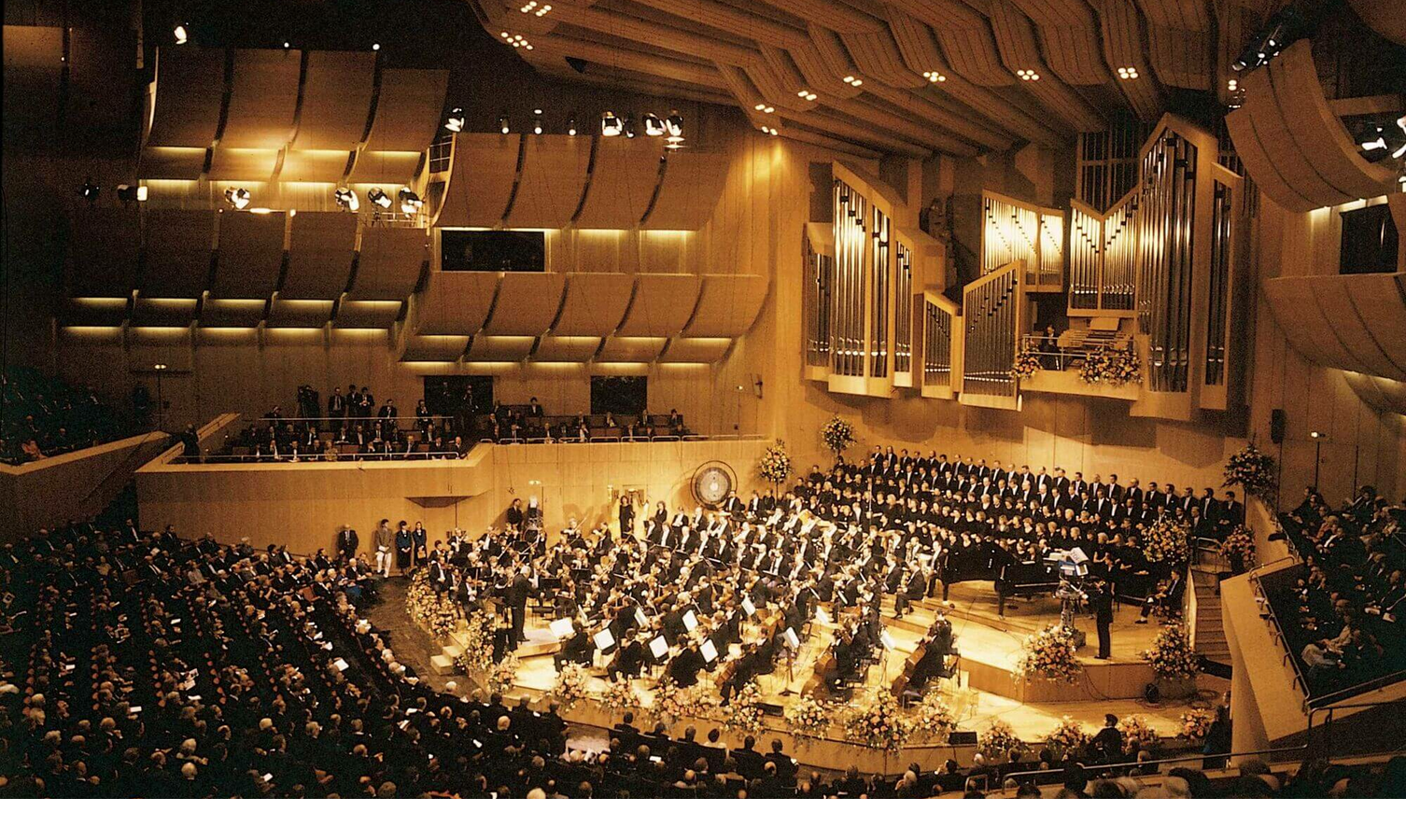 Philharmonie in Gasteig A concert hall with orchestra and choir on stage, surrounded by an audience in a modern, wood-paneled room.