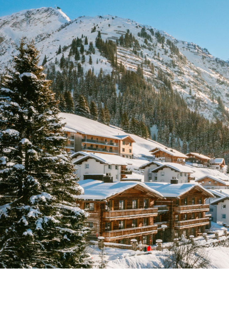 Skipanorama Lech am Arlberg – The Alpine Retreat Verschneite Alpenlandschaft mit Sonne über Hotel Severin*s in Lech, umgeben von Bergen und Bäumen.