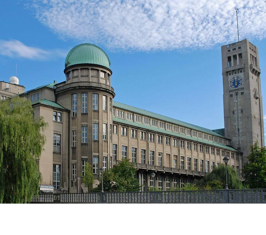 Muca in Munich Historic building with green domed roof and tower clock against a blue sky.